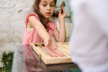 Young girl playing board game with concentration and...
