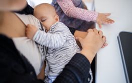 Sleeping baby resting in the arms of her mother while...