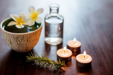 Flowers, candles and bowl of water in spa for self care,...