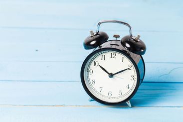 Black vintage alarm clock on wooden table