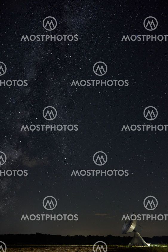 A dish antenna under a clear night sky and the milky way