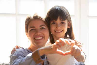 Headshot portrait mother and daughter make heart shape...