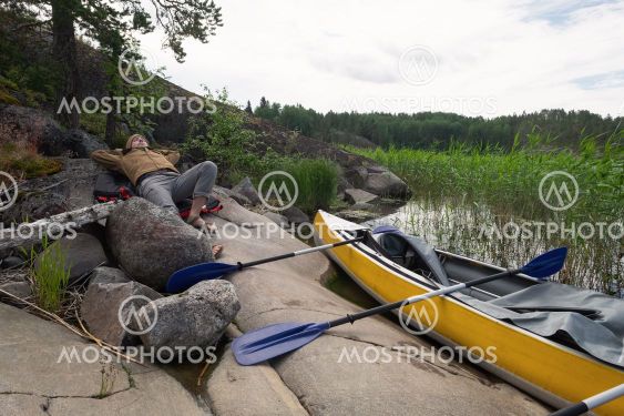 Man resting on the riverside after active paddling on...