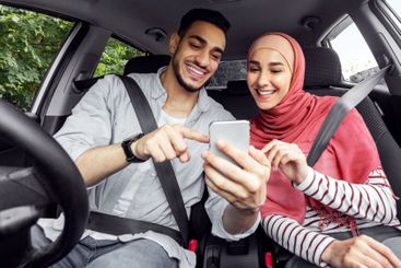 Smiling young arab woman in hijab and guy looking for...