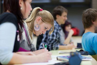 pretty female college student sitting in a classroom full...