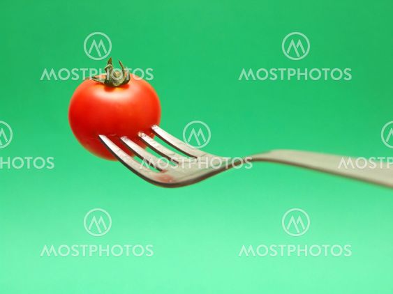 fresh tomato on fork with green background