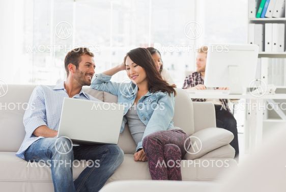 Smiling designers working together on laptop on the couch