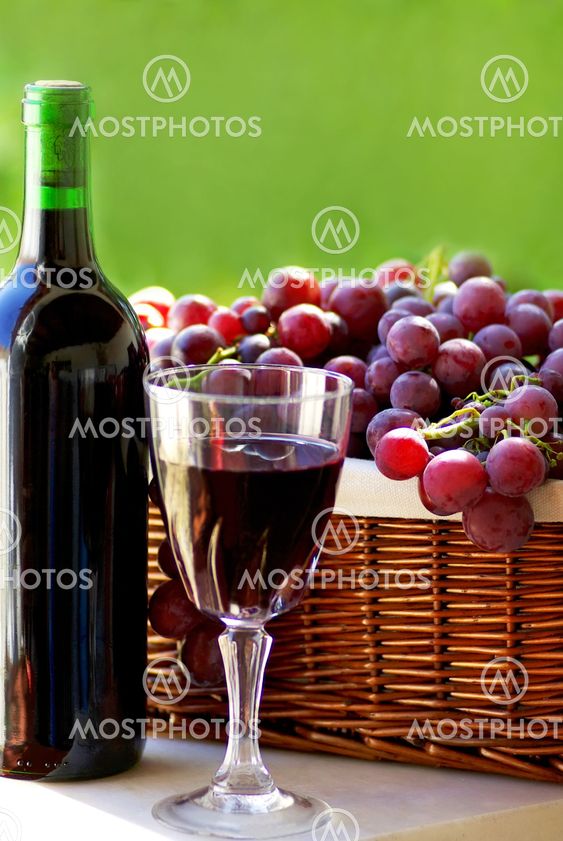 bottle of red wine, a glass of wine and grapes