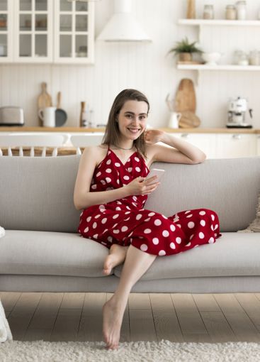 Portrait young female sitting on couch at kitchen...