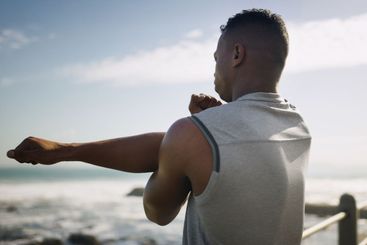 Seaside, man and arm stretching for fitness with warm up...