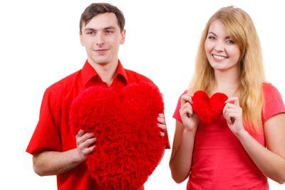 Couple holds red heart shaped pillows love symbol 