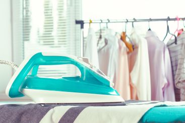 Iron on ironing board on light home interior background