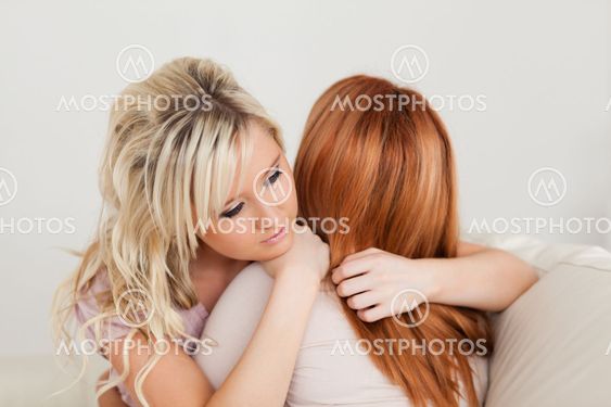 Hugging charming women sitting on a sofa