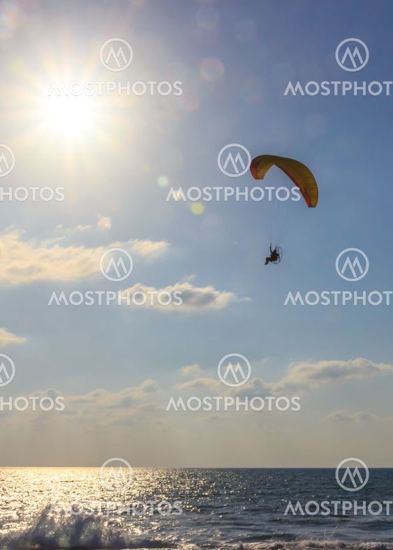parachute jumper on motorized parachute flying over the...