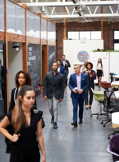 Businesspeople Arriving For Work In Busy Modern Open Plan...