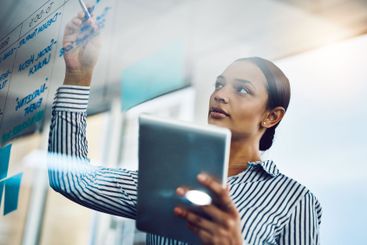 Business, woman and writing on window in office for...