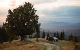 Man near car. Sunset in the mountains