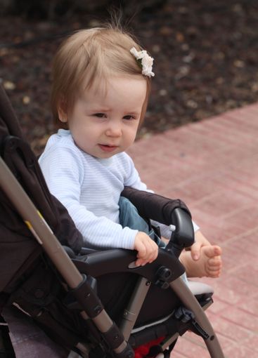 One year old little baby girl smiling in her stroller...