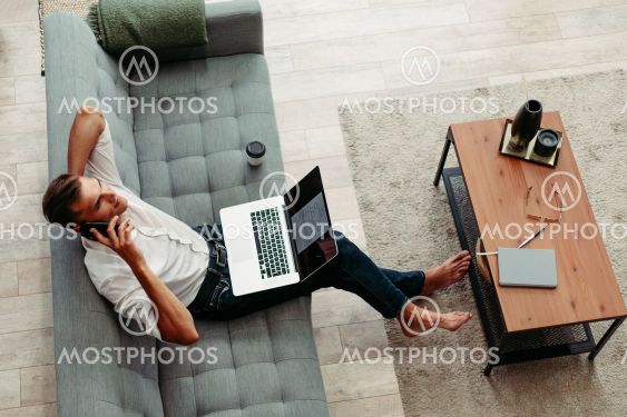 smiling young man is talking on his smartphone .