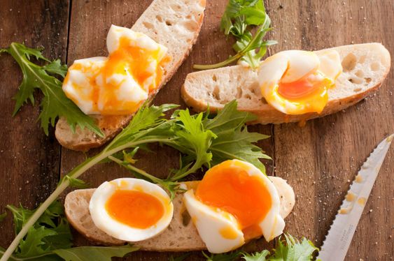 Soft boiled eggs broken open on baguettes