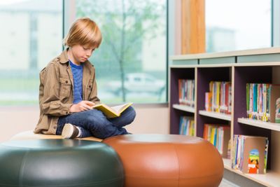 Boy Reading Book In Library