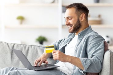 Side view of young Caucasian guy with laptop pc and...