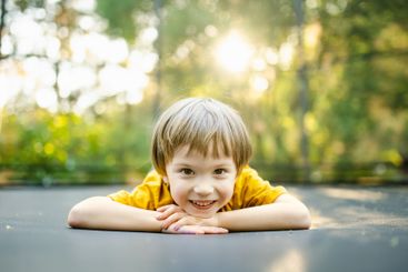 Little boy jumping on a trampoline in a backyard on warm...