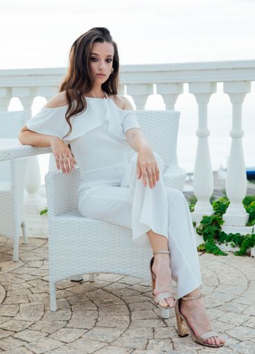 fashionable brunette woman in white suit sitting at...