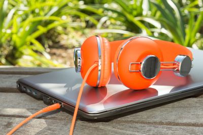 Bright coloured orange headphones and mobile computer
