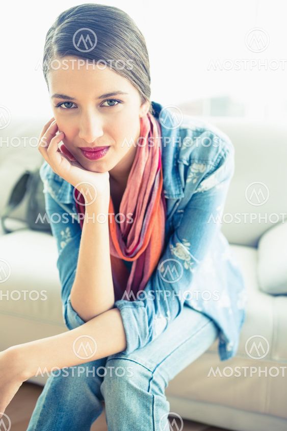 Young brunette sitting on sofa smiling at camera
