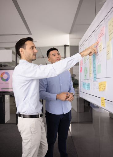 Two male project managers planning tasks on Kanban scrum...