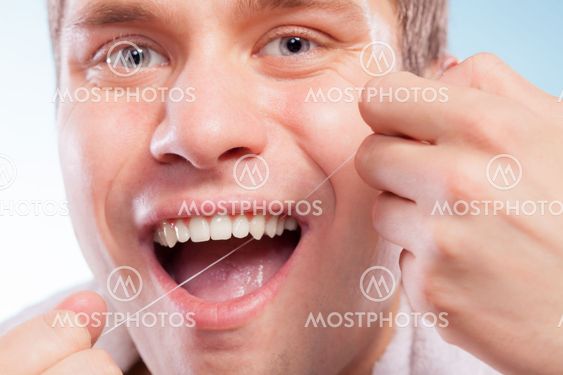 Young man cleaning her white teeth with dental floss