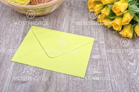 Light green envelope and roses on a wooden background