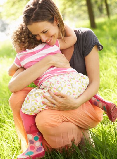 Mother Cuddling Young Daughter In Summer Field