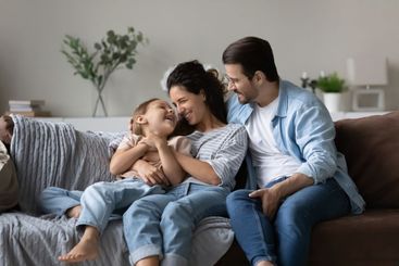 Happy parents with small daughter relax at home