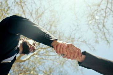 Shaking hands, outdoor and business men with low angle,...