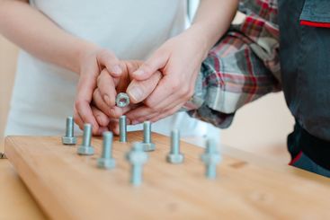Closeup of man in occupational therapy screwing nut on bolt
