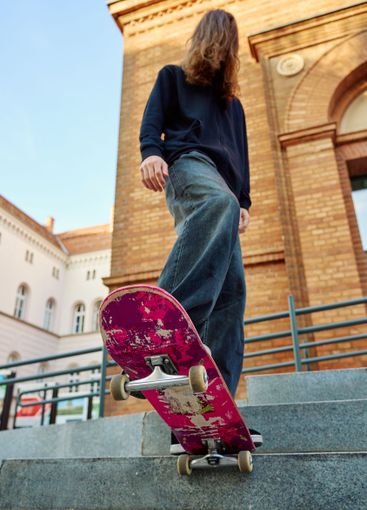 Close-up of skateboarder on pink skateboard at street