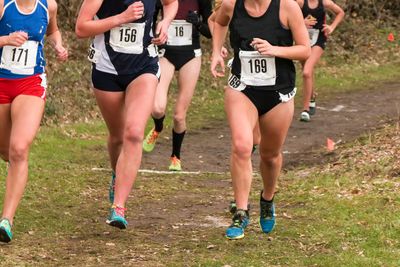High school girls racing cross country race in the woods