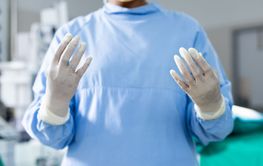 Midsection of surgeon wearing surgical gown and gloves in op