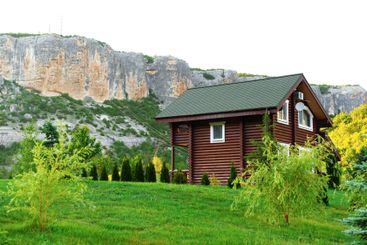 Scenic wooden house with lush green garden and rocky...