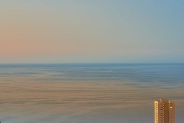 Calm waters during sunset with a hotel building...