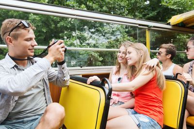 happy friends with camera traveling by tour bus