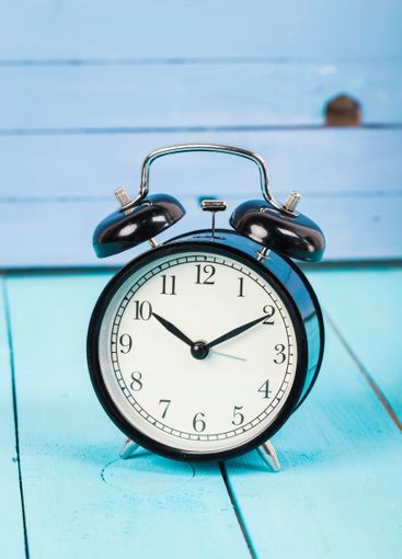 Black vintage alarm clock on wooden table