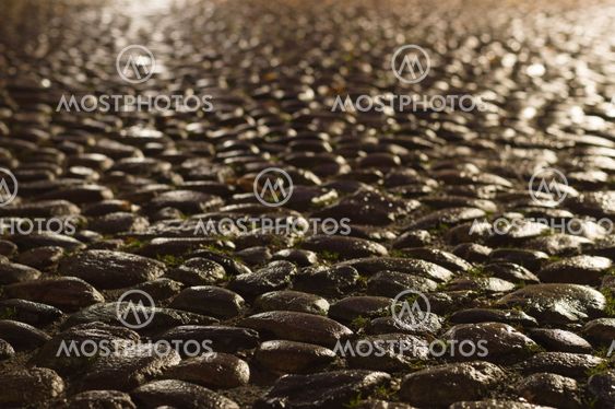Wet ancient cobblestones at night in the light of lanterns