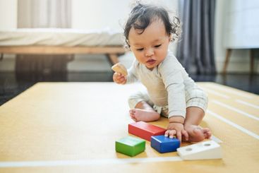 Baby, boy and toy blocks on floor in nursery, childhood...