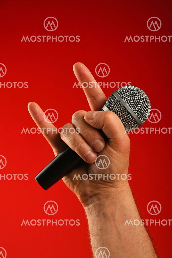 Man hand with microphone and devil horns over red