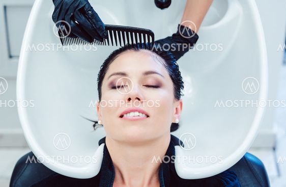 Artisan hairdresser washing hair of customer woman