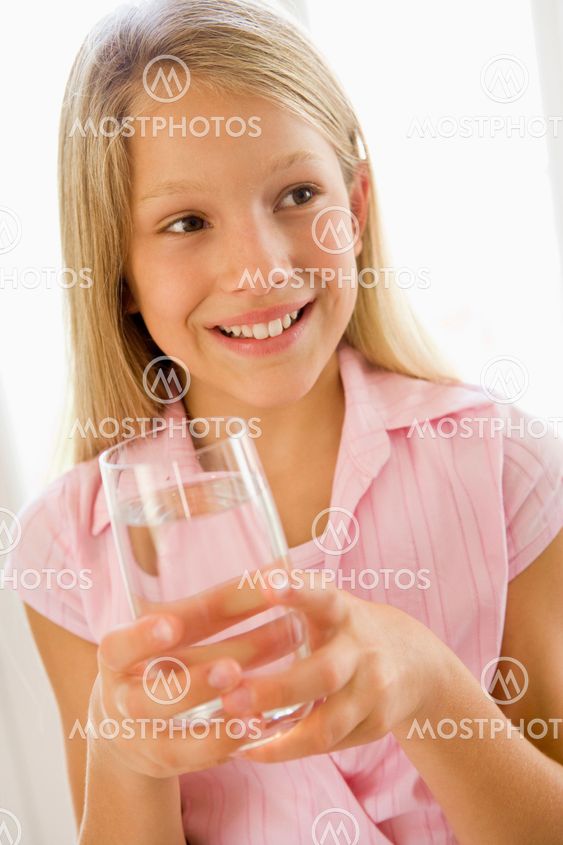Young girl indoors drinking water smiling