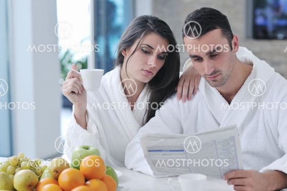Happy couple reading the newspaper in the kitchen at breakfast